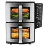 Stainless steel double-drawer air fryer with a digital control panel on the right; top drawer shows salmon and vegetables, bottom drawer shows chicken and fries.