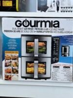 Box for a Gourmia dual-basket air fryer on a shelf; large Gourmia logo, product name in multiple languages, image of a stainless oven with a digital control panel on the front.