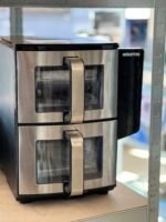 Gourmia stainless steel countertop oven with a glass window and vertical handle on a kitchen shelf.