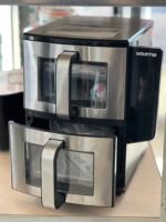 Gourmia stainless steel kitchen appliance with two pull-down doors and glass windows, shown on a countertop.