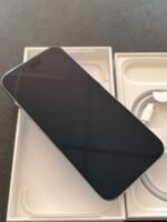 Black smartphone partially removed from a white box, with the charging cable visible in the packaging.