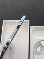 Close-up of a shiny chrome electronic device in a white box, with a braided white cable visible nearby.