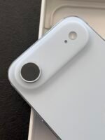 Close-up of a light gray smartphone back showing a circular camera lens and a small mic hole near the top edge.