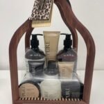 Wooden carrying frame holding a Pure sandalwood body care gift set with pumps, cream tubes, and soaps inside a clear wrap
