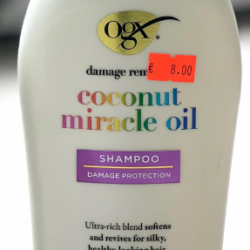 Two OGX coconut miracle oil bottles (left: conditioner, right: shampoo) on a countertop with orange price stickers on each.