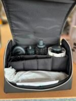 Open camera bag with multiple lens compartments and a folded paper at the bottom area of the bag's interior.