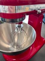 Red Artisan stand mixer with a stainless steel mixing bowl and wire whisk attachment.