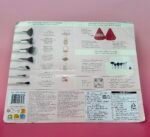 Back of a cosmetic brush set leaflet showing brush illustrations on the left, with small diagrams, multilingual text, barcode, and product info on a pink background.