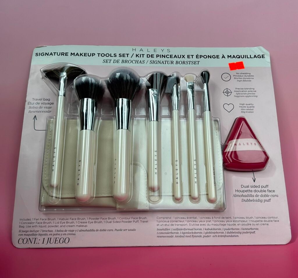 Makeup brush set in a clear plastic case on a pink background, with a light blue header showing 'Signature Makeup Tools Set' text.