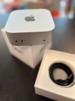 Close-up of a white Apple device with a rounded top and the gray Apple logo, resting on a box.