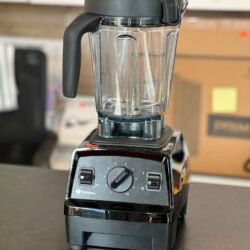 Vitamix blender with a clear pitcher and black lid on a countertop, front control dial visible.