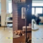 Boxed Dreame Z30 cordless stick vacuum on a table in a bright showroom, with a golden retriever resting at the box’s base.