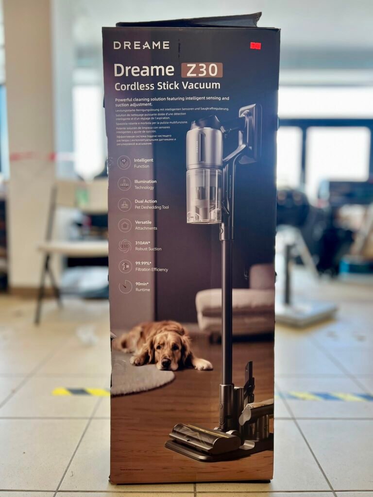 Boxed Dreame Z30 cordless stick vacuum on a table in a bright showroom, with a golden retriever resting at the box’s base.