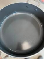 Close-up of a gray nonstick cooking pot interior with a rounded rim and two riveted handles visible at the top edge