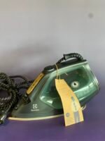 Electric steam iron (Electrolux) with a coiled cord and yellow product tag resting on a purple surface, close-up view of the front and handle area.
