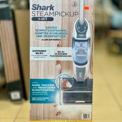 Shark SteamPickup 3-in-1 box on a store shelf showing steam cleaning and disinfection features (German text).