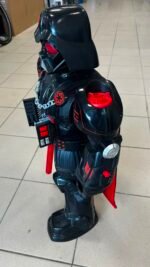 Life-size Darth Vader action figure with black armor and red accents, standing on a tiled floor with a red lightsaber visible in hand or sheath.
