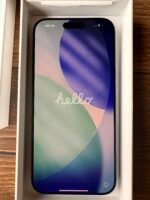 New smartphone in its white box, screen on with a colorful abstract wallpaper and the word 'hello' visible on the display.