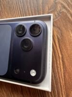 Close-up of a smartphone camera module with three lenses on a dark blue back, resting on a wooden surface