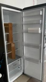 Open refrigerator with several door shelves and empty interior, a few cardboard boxes laying on the left shelves.