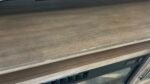 Close-up of a brown wood-grain car door or window frame with minor chips and scratches along the bottom edge.