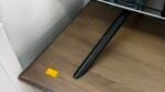 Close-up of a black metal desk leg resting on a brown wooden tabletop with a yellow price tag reading €550.00 attached nearby.
