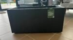 Large black outdoor storage box with a green Deroma Millennium tag attached to the side of the box in a showroom setting