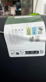 Millennium label on a black device showing icons for recycling, water saving, mosquito prevention, and indoor/outdoor use with a size chart nearby.