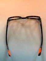 Tortoiseshell eyeglass frame laid flat, showing front and orange temple tips