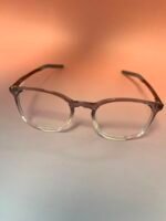 Clear-framed eyeglasses with brown temples resting on a peach gradient background.