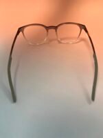 Close-up of clear-framed eyeglasses resting on a peach background.