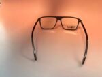 Black-rimmed eyeglasses lying on a pale pink surface, viewed from above by the lenses