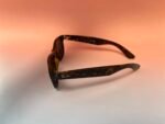 Brown tortoiseshell Ray-Ban sunglasses with rectangular frames resting on a light surface, logo visible on the arm.