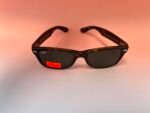 Ray-Ban tortoiseshell sunglasses on a pink background with a red price sticker showing 80.00 on the lens area