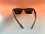 Tortoiseshell sunglasses with dark lenses lying on a light surface against an orange gradient background.