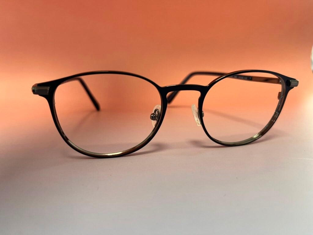 Close-up of black round eyeglasses resting on a warm orange background.