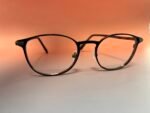Close-up of black round eyeglasses resting on a warm orange background.