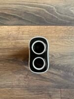Top-down view of a black triple-lens camera accessory with three circular lenses on a wooden surface.