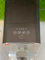 Close-up of a black coffee machine control panel with five cup icons and a circular power button below them.