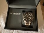 TAG Heuer watch in black box; stainless steel bracelet, black dial with sub-dials, tachymeter bezel, logo visible on face and inside lid.