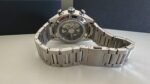 Stainless steel wristwatch with a transparent case back showing the inner gears, resting on a light surface.
